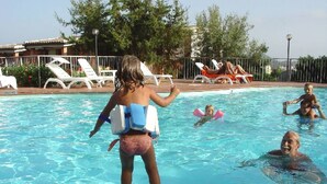 A swimming pool with lounge chairs and a fence. - Residence la Chimera (Villasimius)