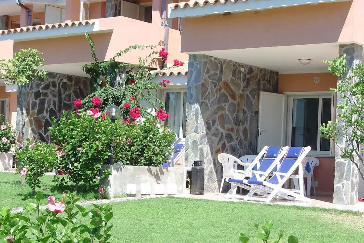 A hotel with a stone facade, outdoor seating, and a well-maintained garden.