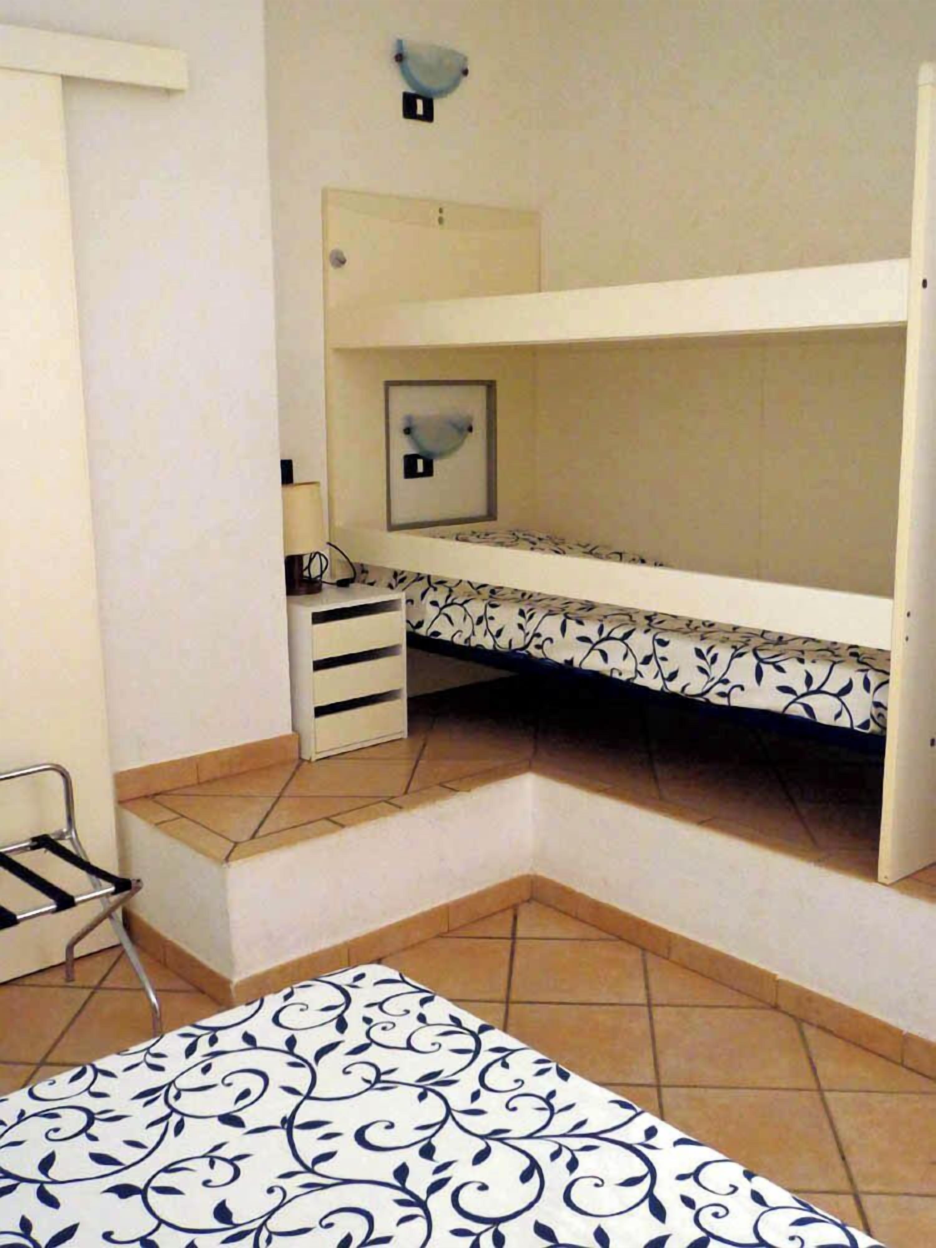 A small, compact room with a bunk bed, a desk with drawers, and a chair.