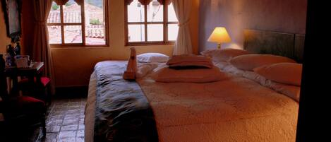 Una habitación de hotel con cama, mesita de noche, lámpara y ventana con cortinas.