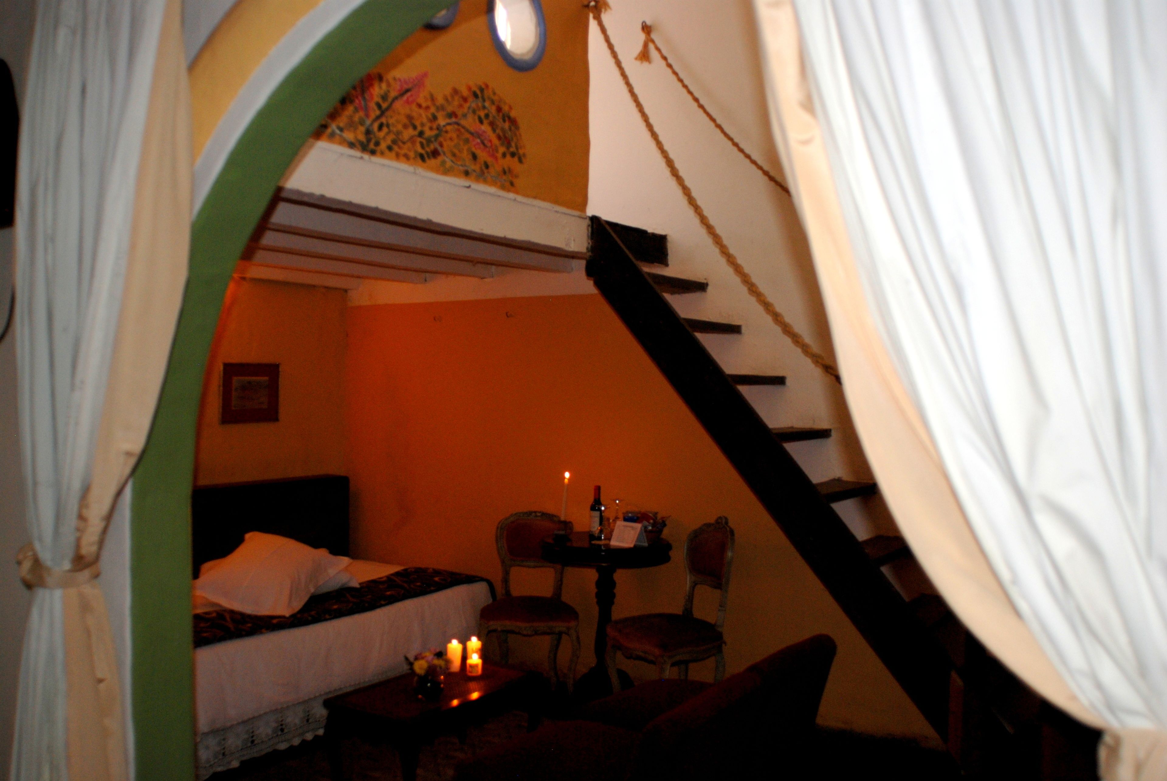 A room with a bunk bed, a small table with candles, and a chair.