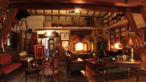 A cozy, traditional living room with a fireplace, wooden beams, and a variety of seating options.