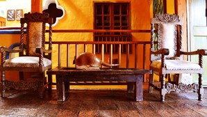 A room with two ornate wooden chairs, a wooden bench, and a large shell on the bench.