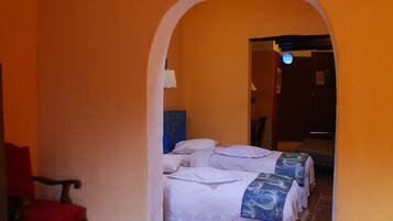 A corridor with a bed at the end, a red chair, and a lamp.