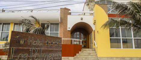 Entrada de un hotel con un letrero que dice "Hotel Las Palmas" y una escalera que conduce a la entrada.