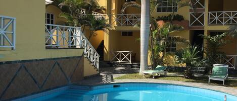 Una piscina rodeada por un edificio con balcones y palmeras.