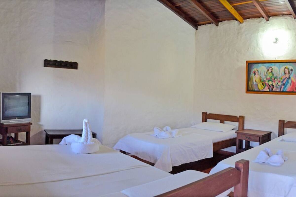 Una habitación con tres camas, un televisor y un cuadro en la pared.