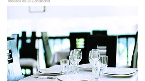Mesa de comedor de hotel dispuesta con platos, vasos y cubiertos.