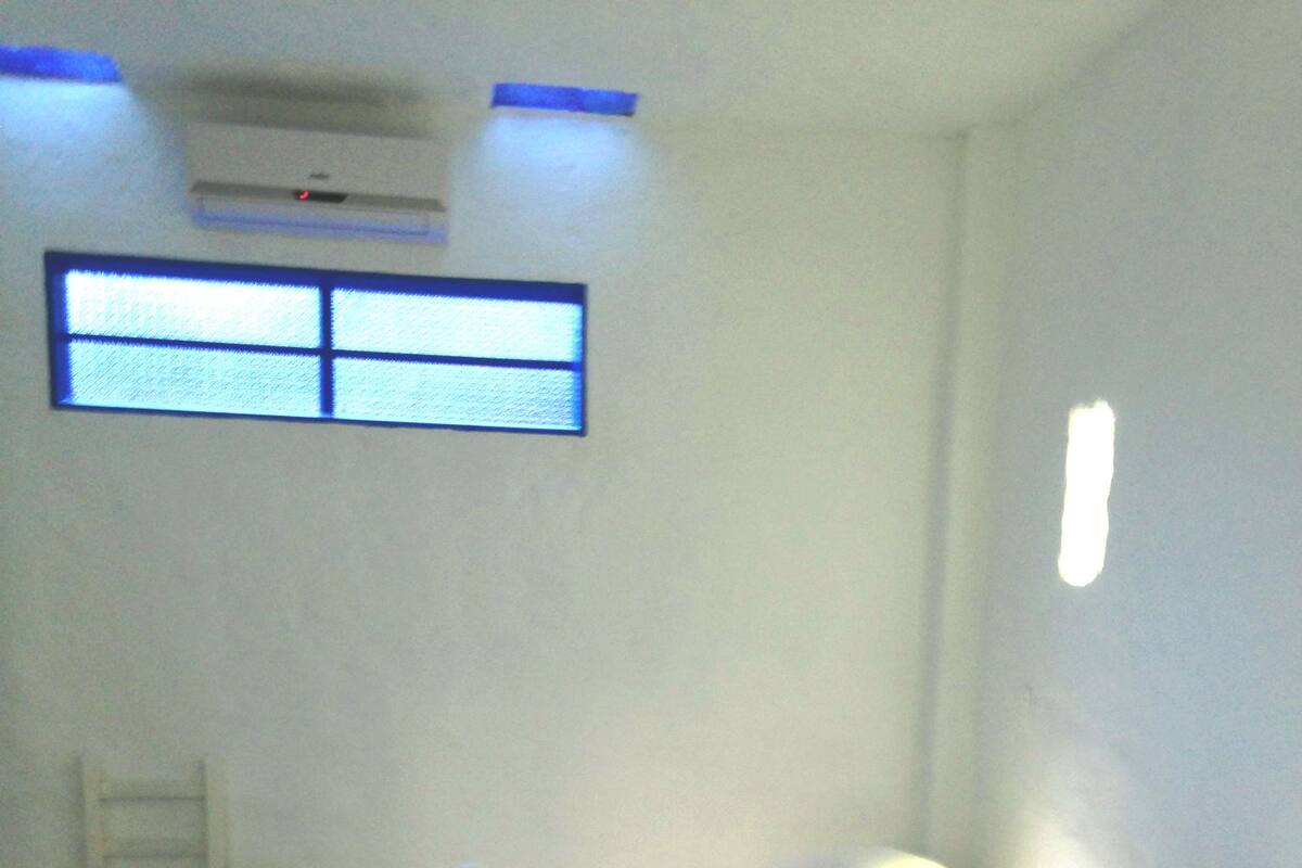Habitación de hotel con dos camas, una silla y un ventanal.