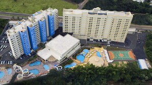 A high-rise hotel with multiple floors, a swimming pool area, and a basketball court. - Golden Dolphin Grand Hotel OFICIAL (Caldas Novas)