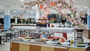 A buffet setup with various food items and a decorative cherry blossom arch. - Golden Dolphin Grand Hotel OFICIAL (Caldas Novas)