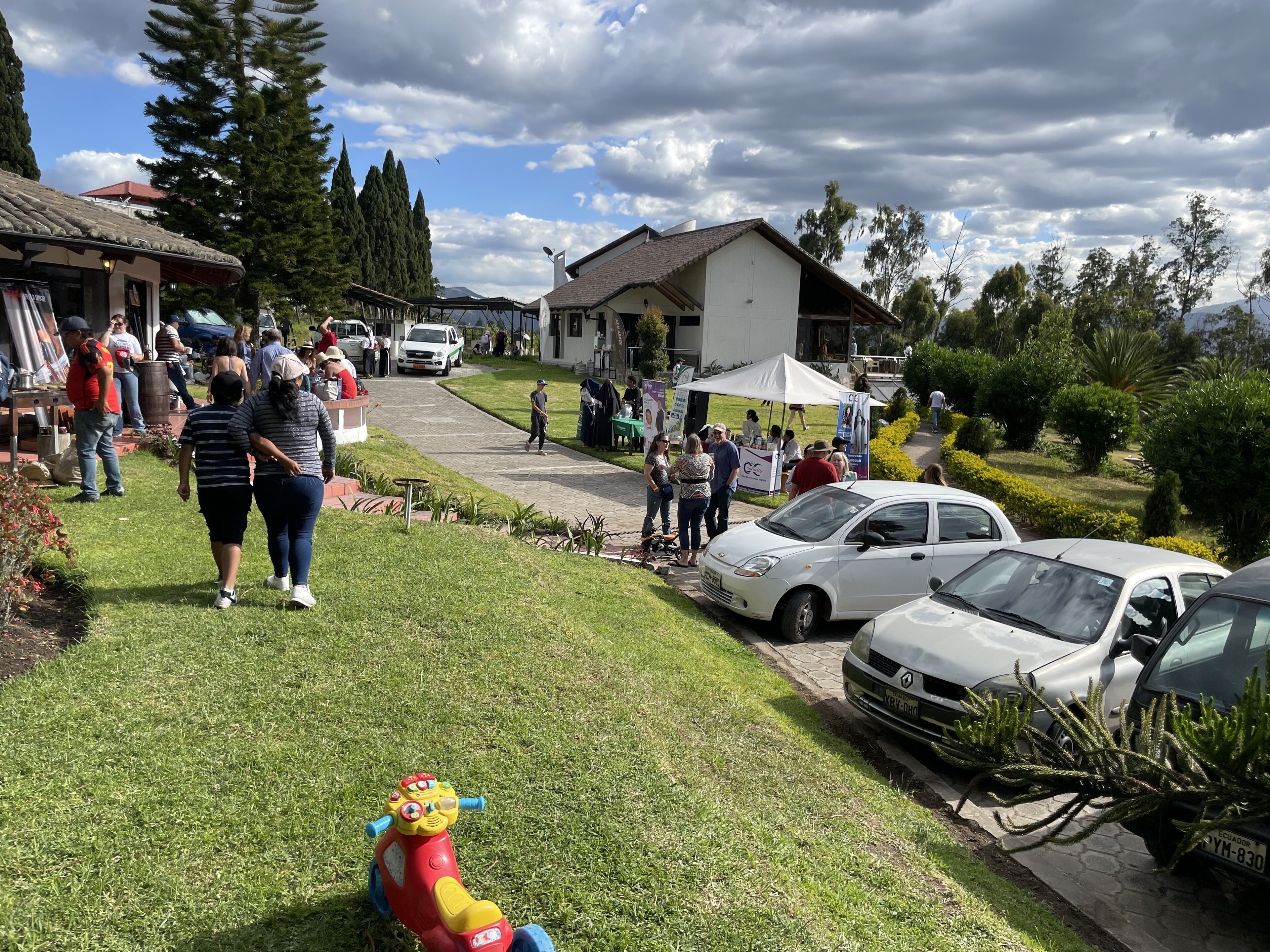 A parking area with several cars and a small child’s toy car.