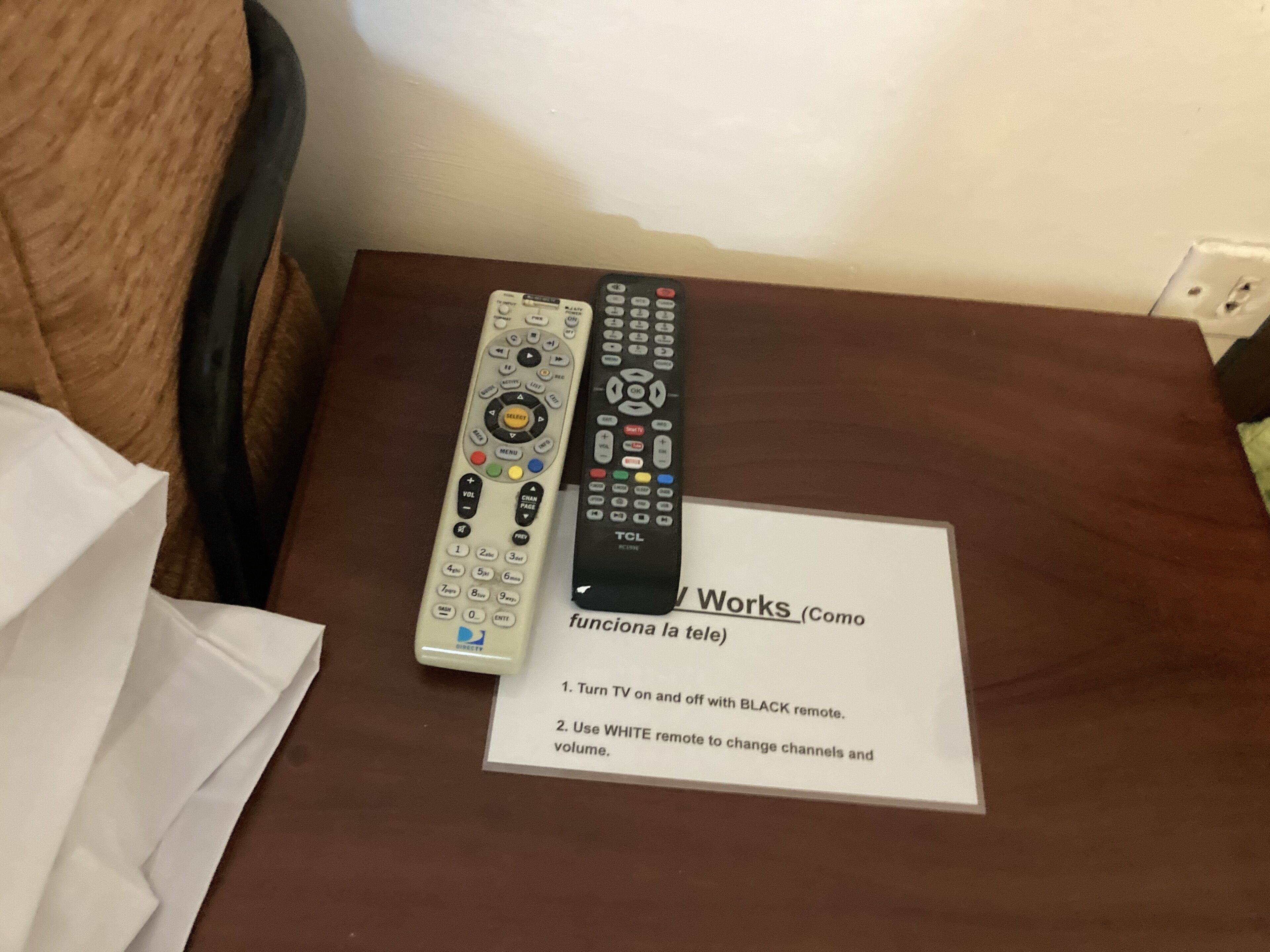 Dos controles remotos y un papel con instrucciones sobre una mesa marrón.