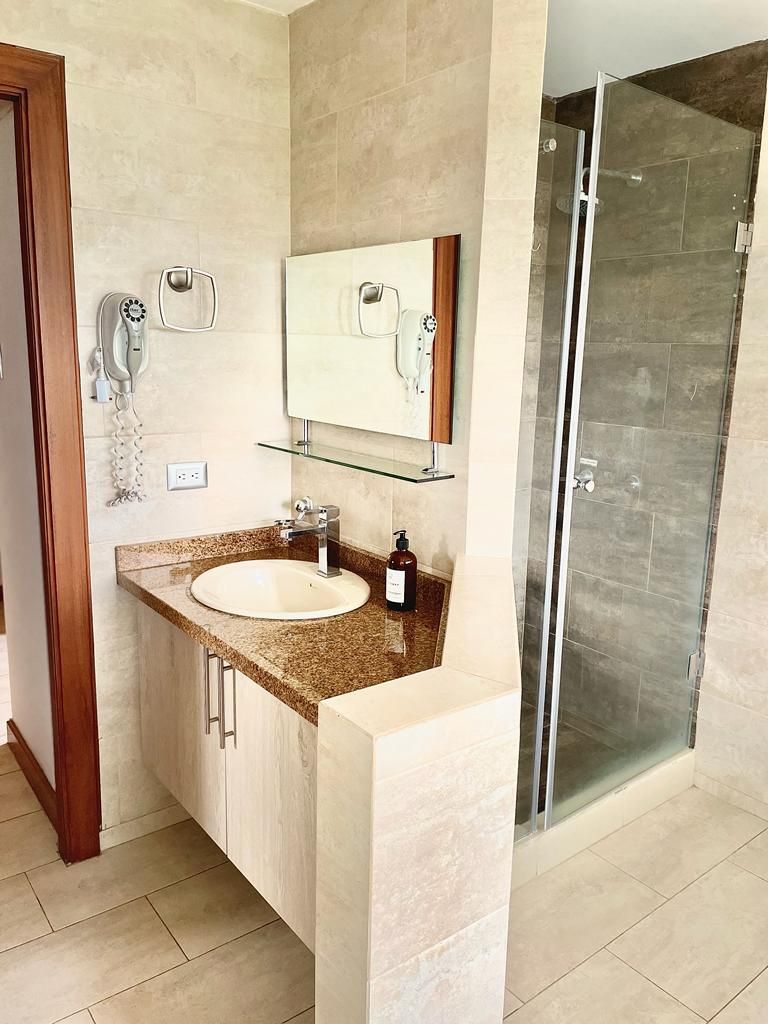 A bathroom with a sink, mirror, and glass shower enclosure.