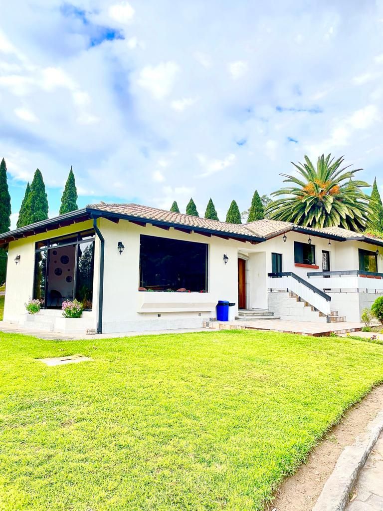 Una casa moderna de dos pisos con techo de tejas, patio cubierto y césped bien cuidado.