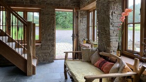 Una habitación rústica con pared de piedra, escalera de madera y cama con almohadas.
