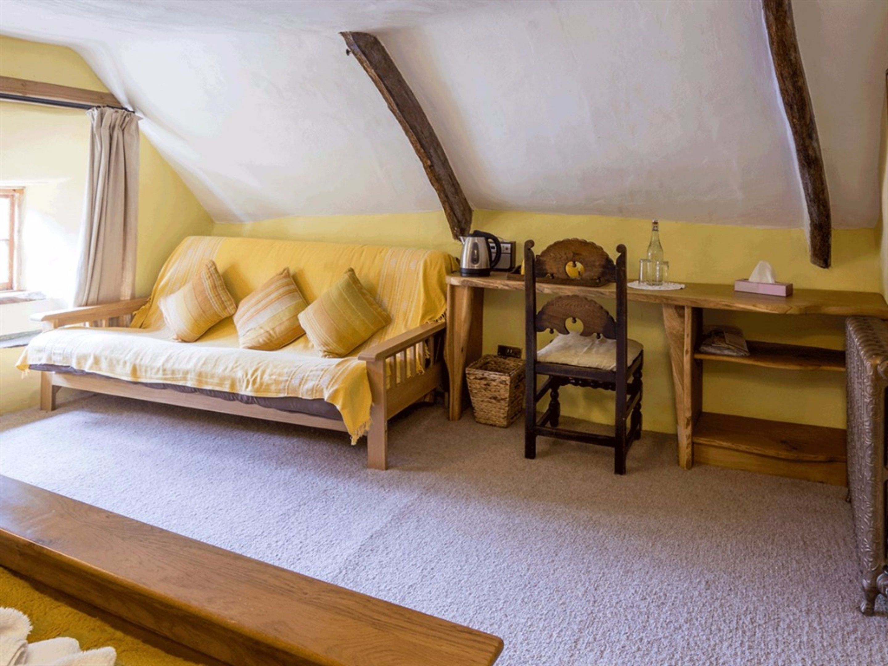 A cozy attic bedroom with a wooden bed, a chair, and a small table.