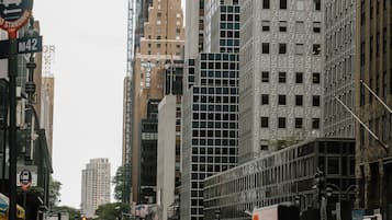 Una concurrida calle urbana con edificios altos, incluyendo un hotel con un cartel que indica que lo es.