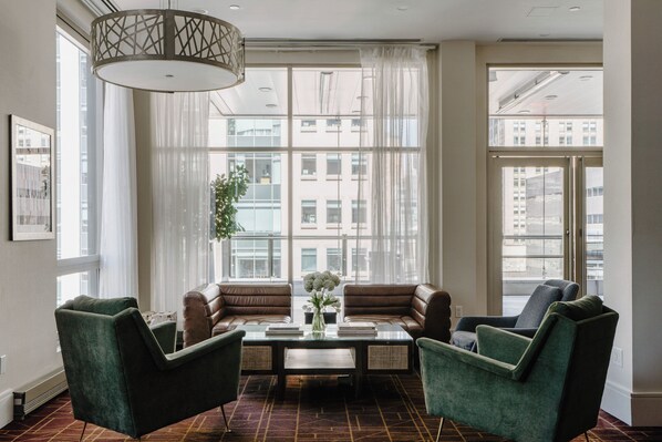 A modern hotel room with a large window, a sofa set, a coffee table, and a hanging light fixture. - Club Quarters Hotel, Grand Central (New York)