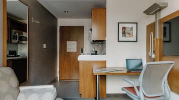 Una habitación de hotel moderna con kitchenette, zona de comedor y área de descanso.