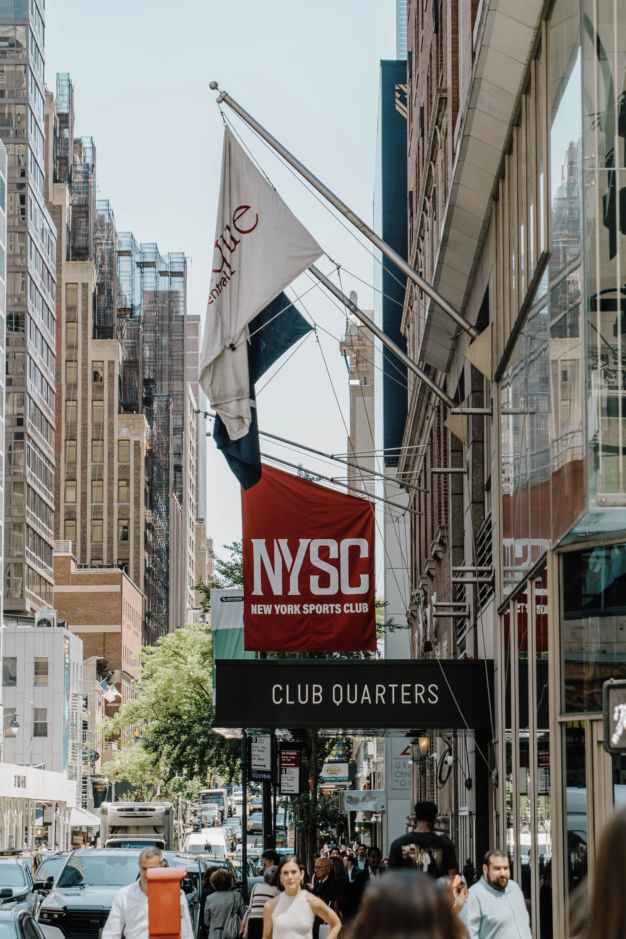 A street view with a NYSC New York Sports Club sign and a Club Quarters sign.