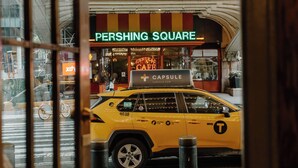 Um táxi amarelo estacionado em frente a um edifício com uma placa que diz 'PERSHING SQUARE'.