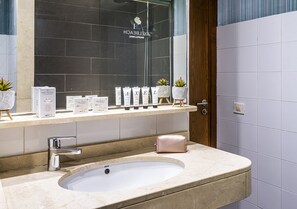 A modern bathroom with a large sink, a mirror, and a shelf with toiletries.