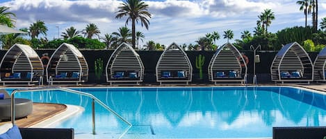 Una piscina al aire libre, sombrillas, tumbonas