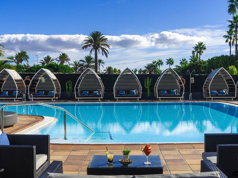 Una piscina al aire libre, sombrillas, tumbonas