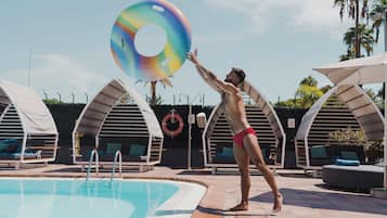 Un área de piscina con sillones de descanso y sombrillas.