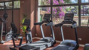 Un gimnasio con cintas de correr, elíptica y bicicleta estática.