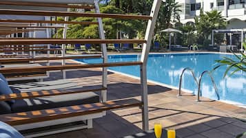 Zona de piscina con sillones de descanso y una mesa con dos vasos de zumo de naranja.