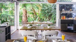 Una mesa para dos lista para el desayuno, con platos, tazas y una bandeja de fruta.
