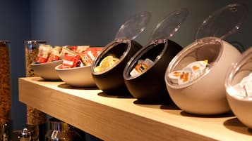 Una barra de buffet con distintos alimentos servidos en cuencos y recipientes.