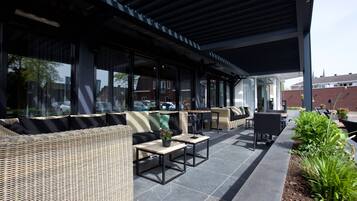 An outdoor seating area with wicker furniture, tables, and a covered patio.