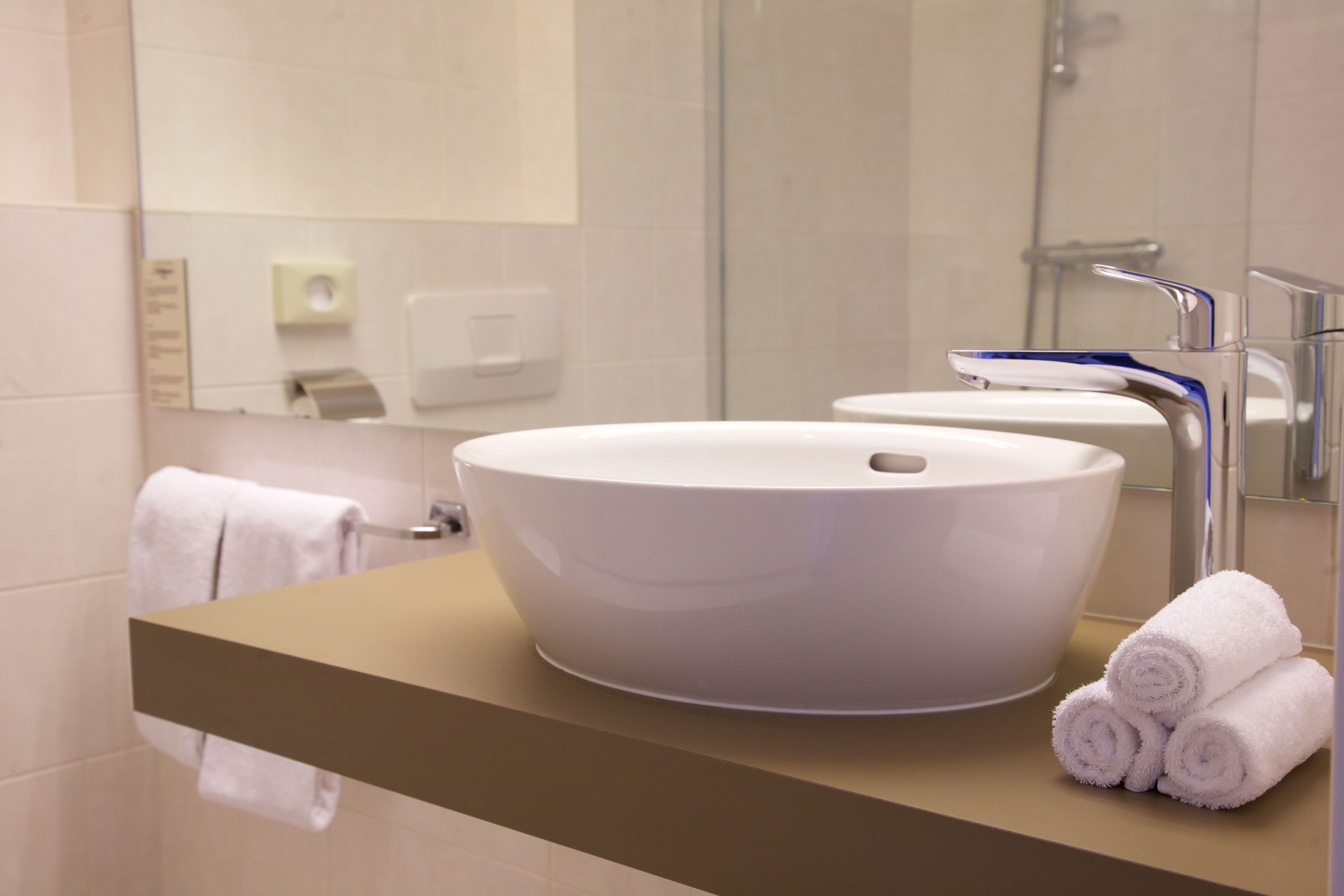 Un baño moderno con un lavamanos grande de color blanco, un espejo y un perchero para toallas.