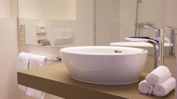 Un baño moderno con un lavamanos grande de color blanco, un espejo y un perchero para toallas.
