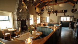 A restaurant with a stone fireplace, wooden bar, and seating area.
