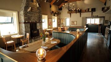 A restaurant with a stone fireplace, wooden bar, and seating area.