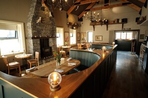 A restaurant with a stone fireplace, wooden bar, and seating area.