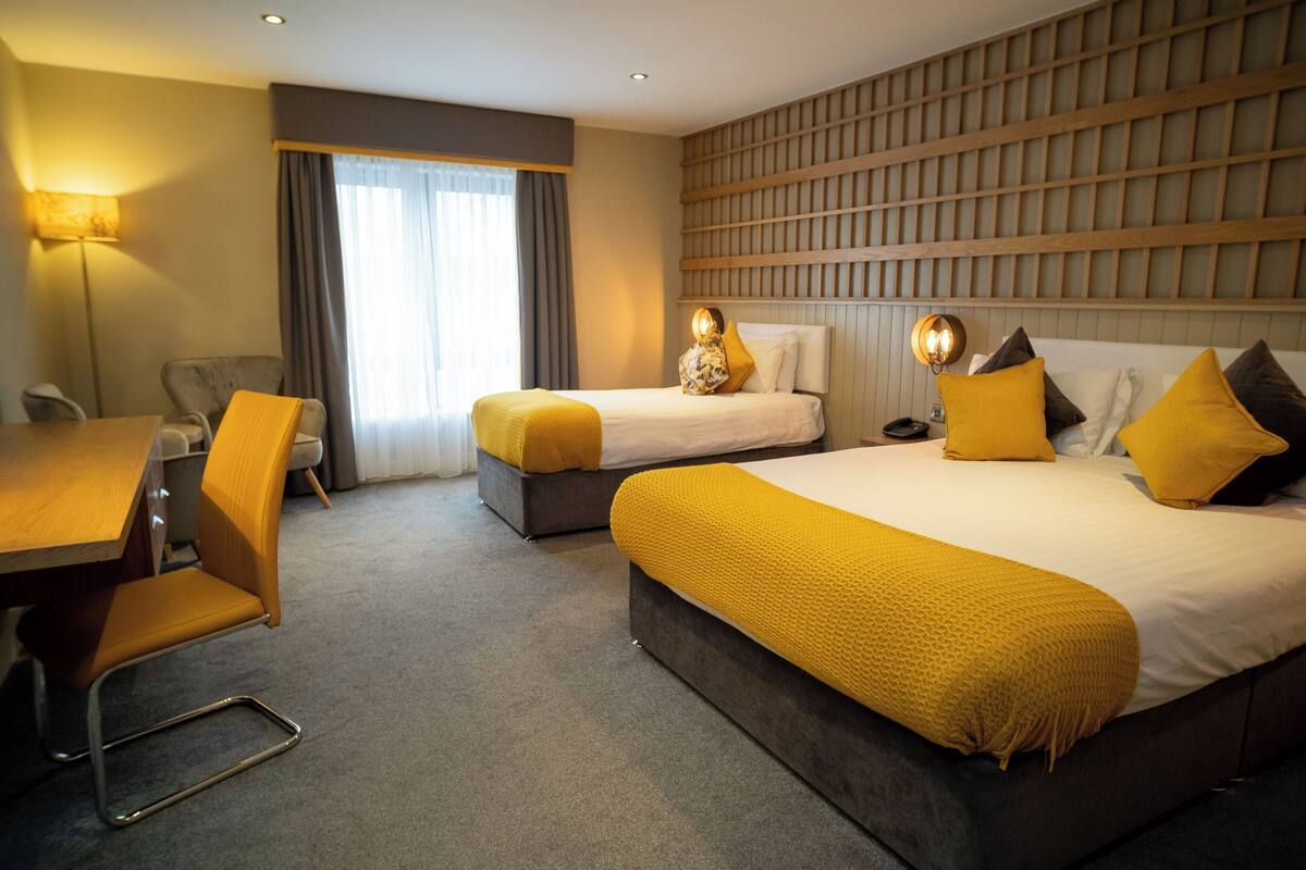 A hotel room with two beds, a desk, and a chair.