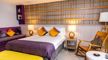 A hotel room with a bed, a seating area with a sofa and armchairs, a small table, and a wall with a wooden panel design.