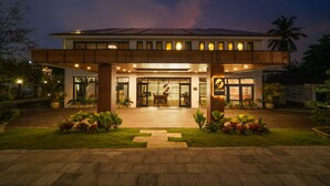 A modern hotel with a two-story structure, a covered entrance, and a well-maintained garden.