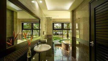 A modern bathroom with a large mirror, a sink, and a shower area.