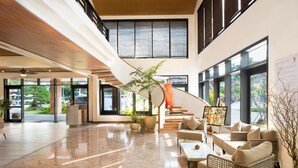 A spacious lobby with a high ceiling, a staircase, and a seating area with sofas and a coffee table.