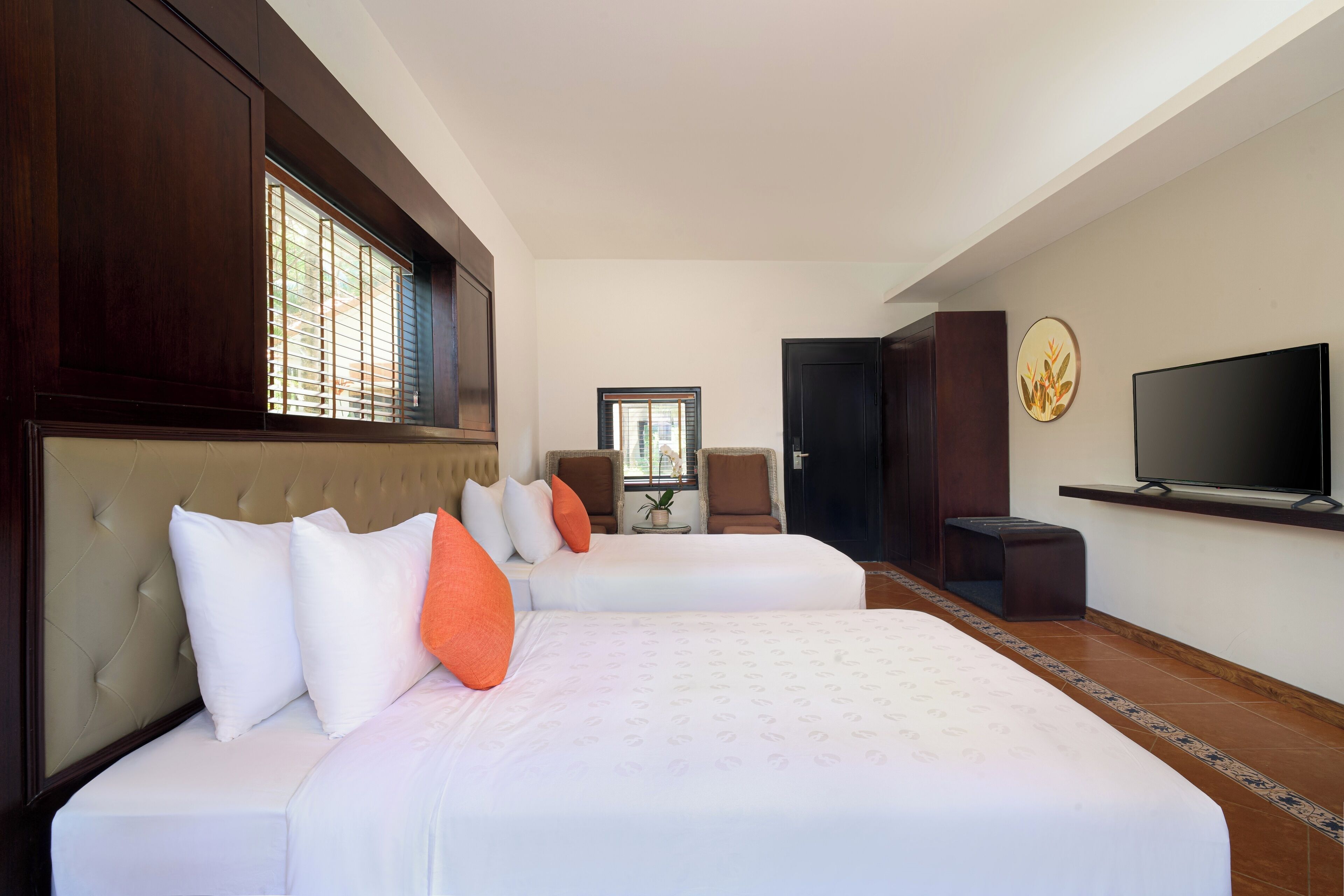 Une chambre d’hôtel avec deux lits, une télévision et un coin salon comprenant des chaises et une table.