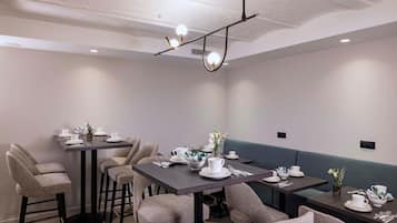 A dining area with multiple tables and chairs, each set with white tableware and small decorative items.