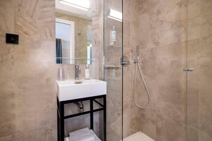 A modern bathroom with a glass-enclosed shower, a white sink, and a mirror above it.