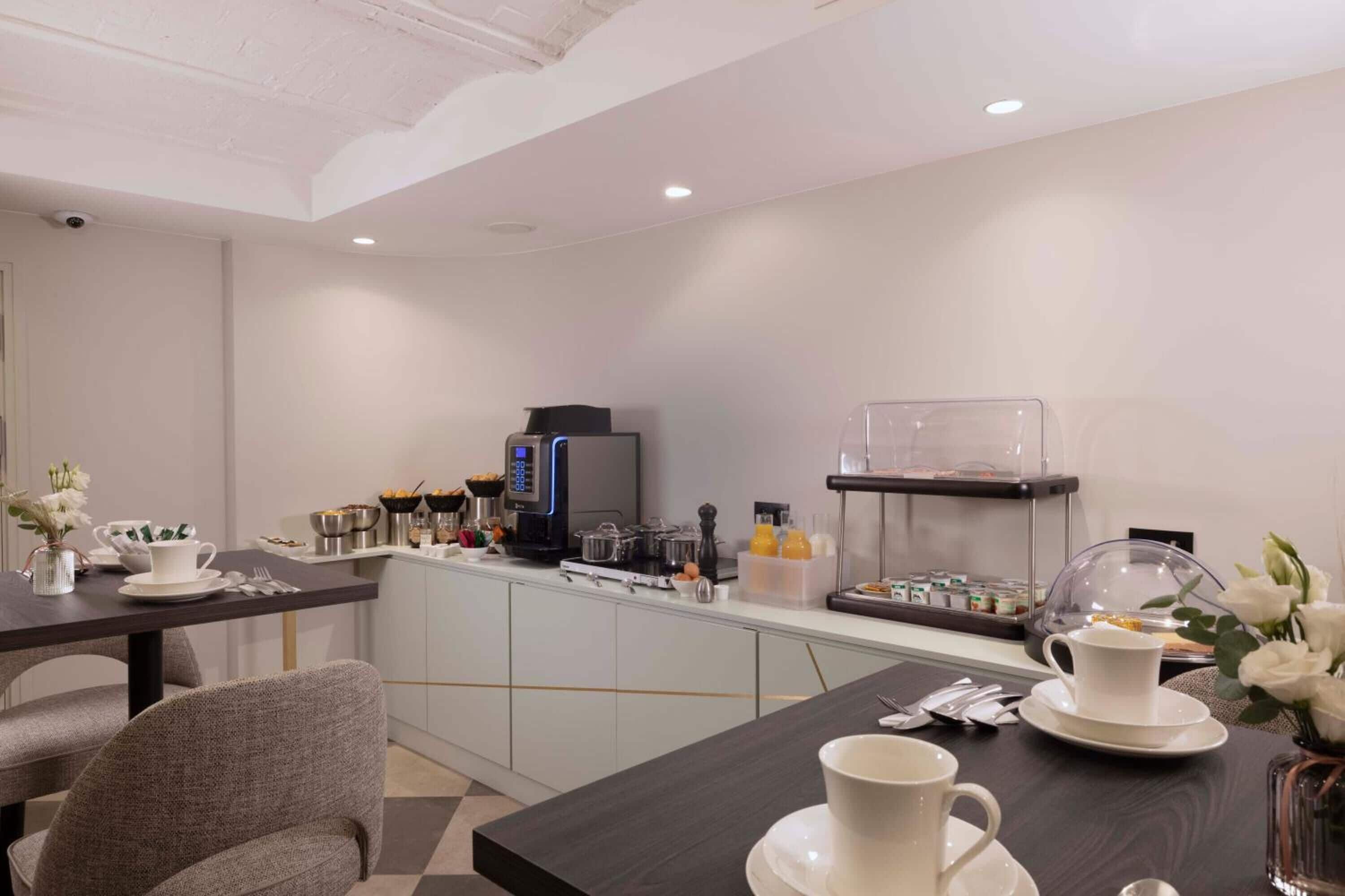 Een moderne keuken met een koffiehoek, een eethoek met een tafel en stoelen, en een aanrecht met diverse keukenapparaten.