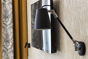 A wall-mounted television with a black lamp beside it.